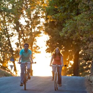 Couple riding bicycles, sunset behind them